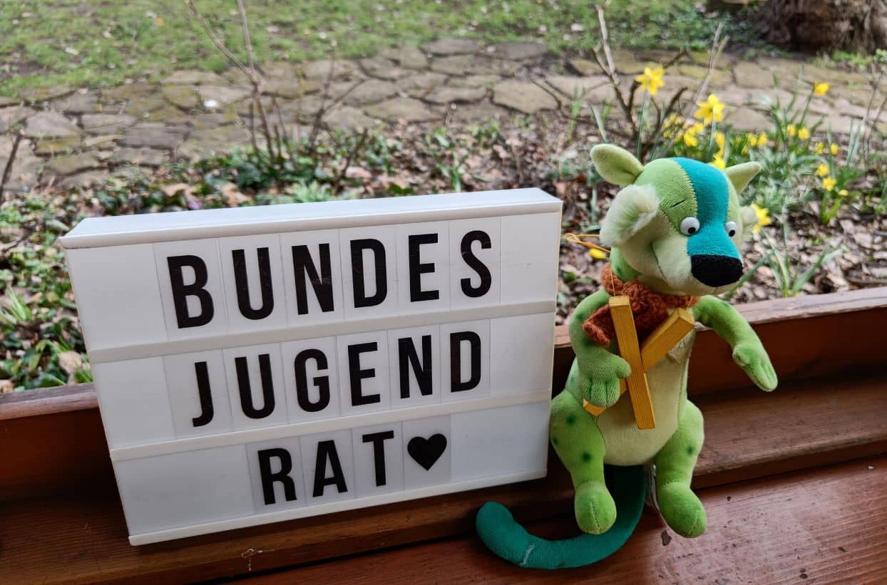 Bundesjugendrat Schild und Stofftier im Garten.
