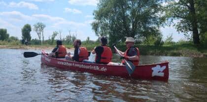 Personen paddeln im roten Kanu auf Wasser