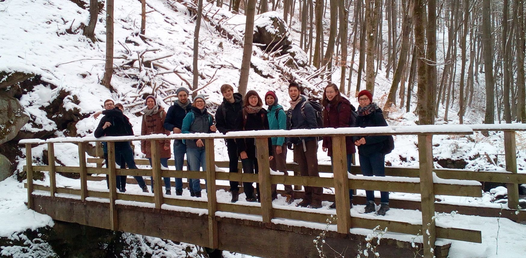 Gruppe auf Holzbrücke im winterlichen Wald