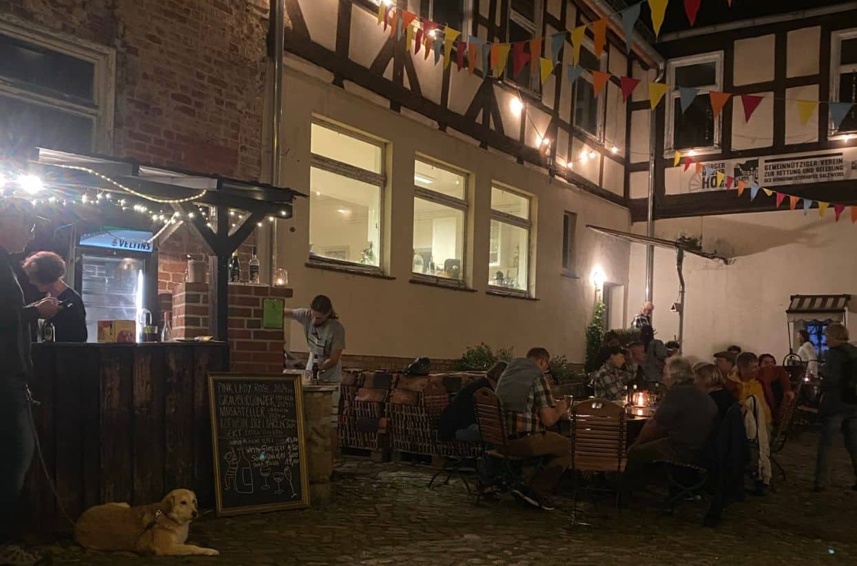 Gemütlicher Hof bei Nacht mit Gästen und Hund