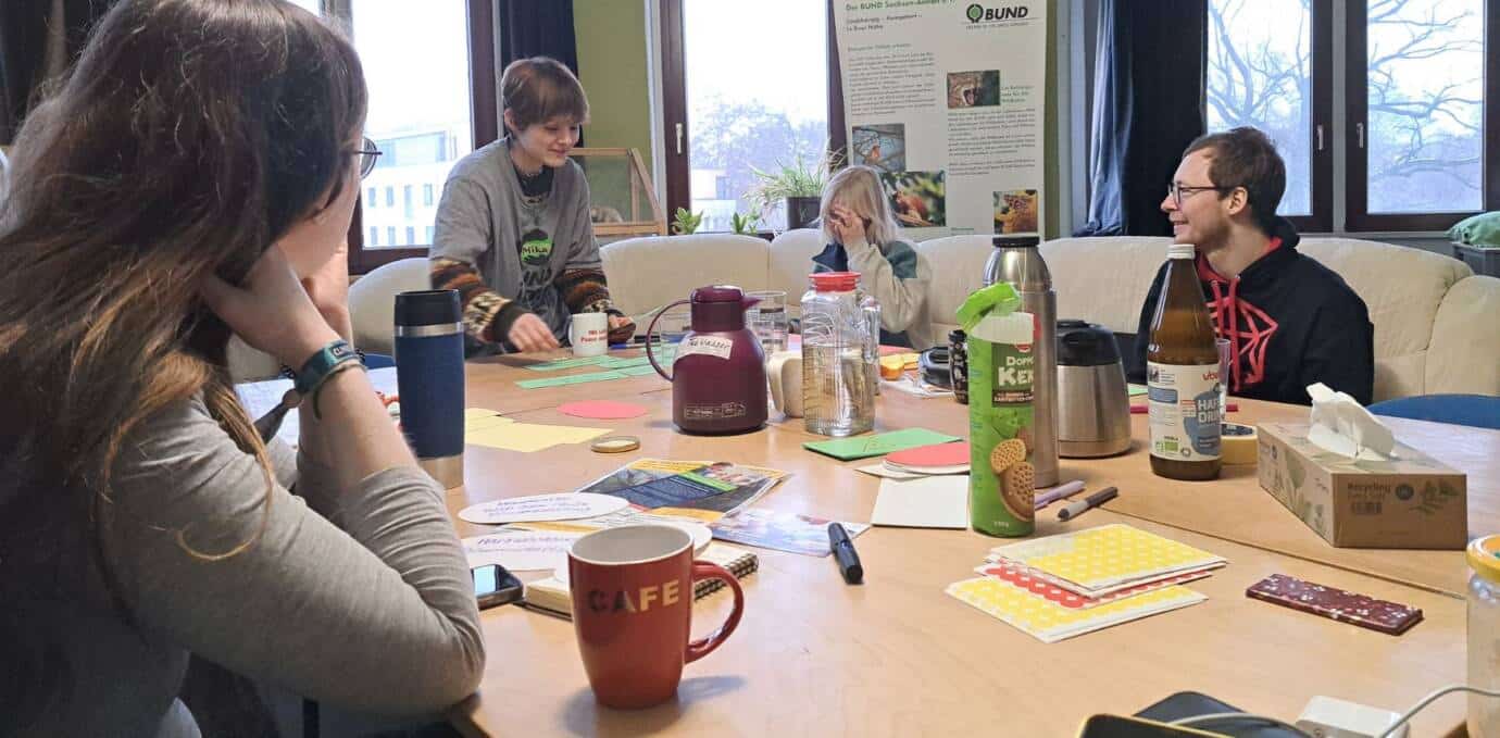 Gruppe diskutiert an einem Tisch mit Getränken.