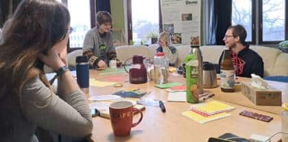 Gruppe diskutiert an einem Tisch mit Getränken.